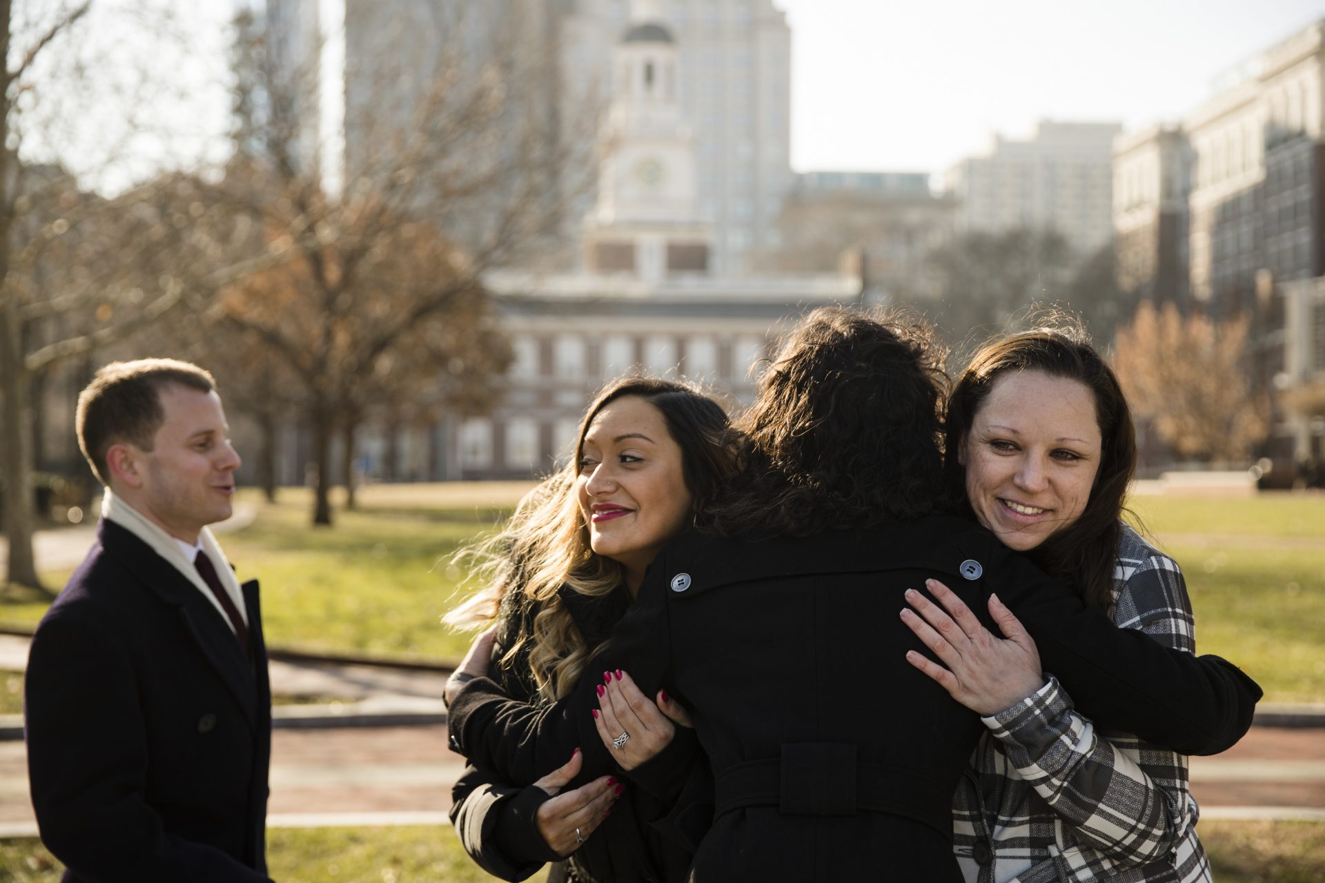 An attorney with the Institute for Justice, Erica Smith, center right, embraces Courtney Haveman, center, and Amanda Spillane, right as lawyer Andrew Ward looks on during a news conference in view of Independence Hall in Philadelphia.
