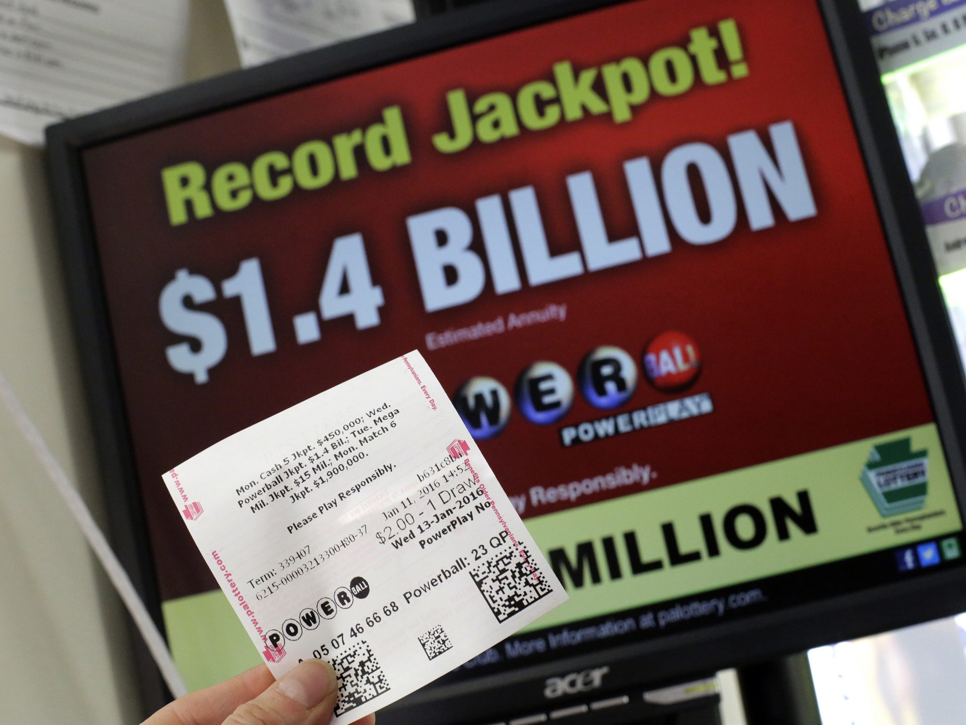 A Powerball ticket purchased in a convenience store in Lancaster, Pa., is held in front of a Pennsylvania Lottery computer screen advertising the record $1.4 billion Powerball jackpot, Jan. 11, 2015, in this file photo.