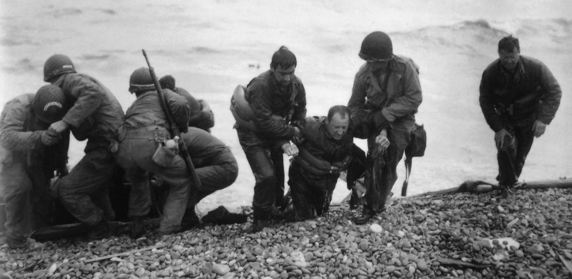 Members of an American landing unit help their exhausted comrades ashore during the Normandy invasion on June 7, 1944. Nick Russin is pictured in the center being dragged onto shore.