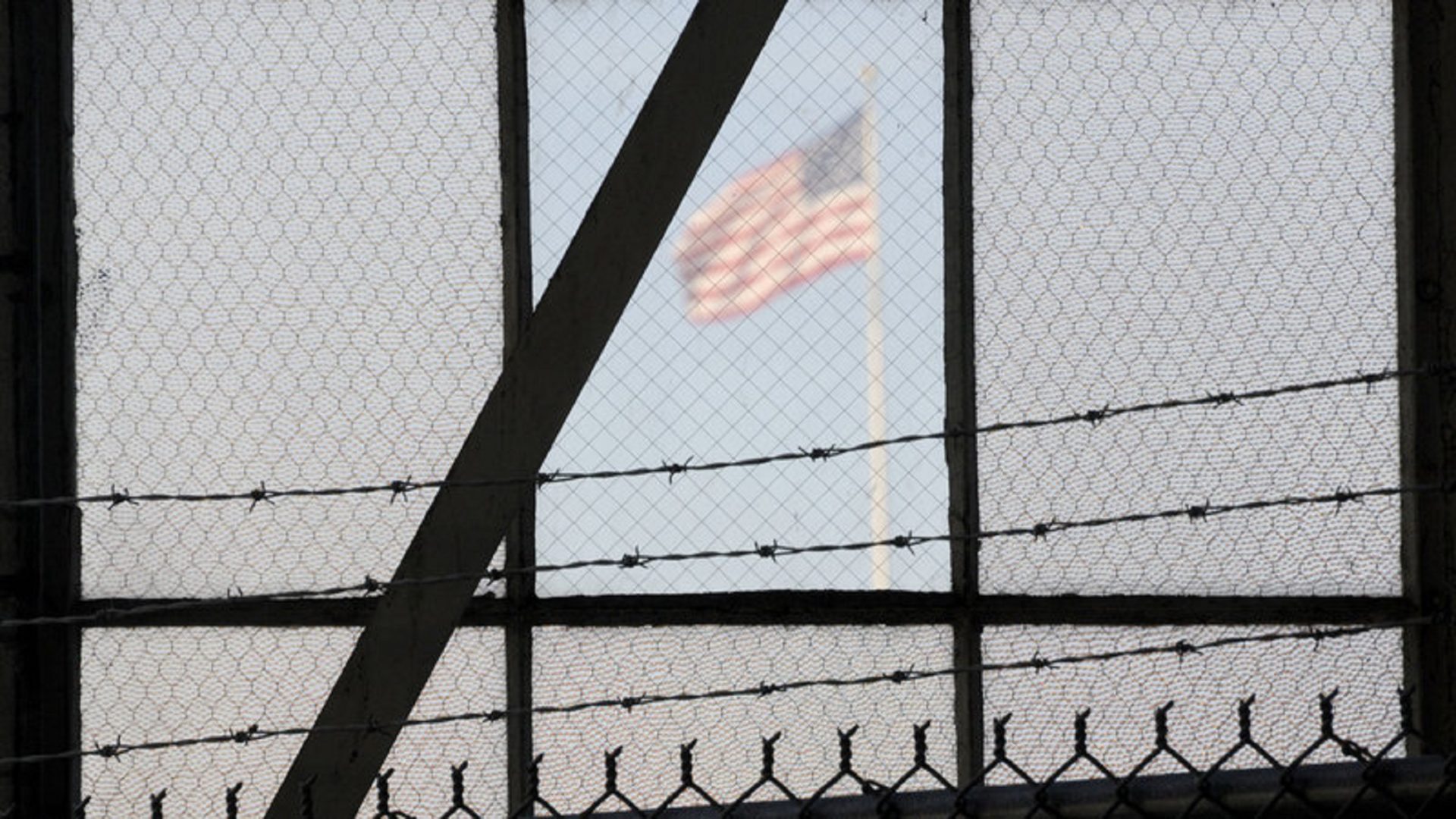 An NPR investigation finds that the military court and prison at GuantÃ¡namo Bay, Cuba, have cost taxpayers billions of dollars, with billions more expected. Above, an American flag is seen through the war crimes courtroom at the U.S. naval base at GuantÃ¡namo Bay on Oct. 17, 2012.