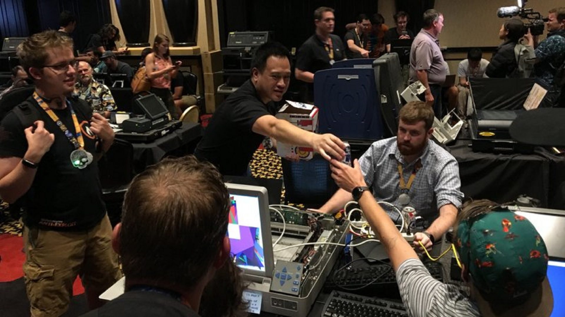 Hackers at this year's Def Con pass out beer as they mess with a voting machine that was used in last year's midterm elections in Virginia.