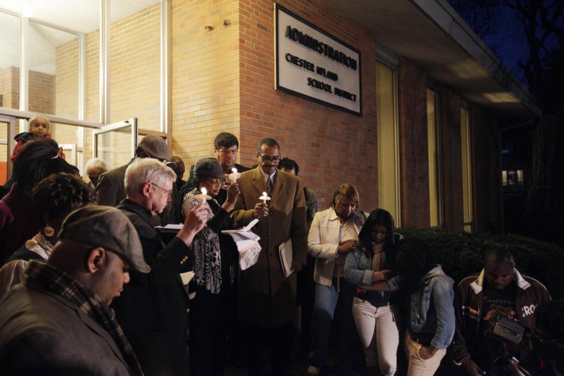 In this Thursday, Jan. 12, 2012 photo, parents, teachers and other community members participate in a candlelight vigil outside the Chester-Upland School District administration building in Chester, Pa. 