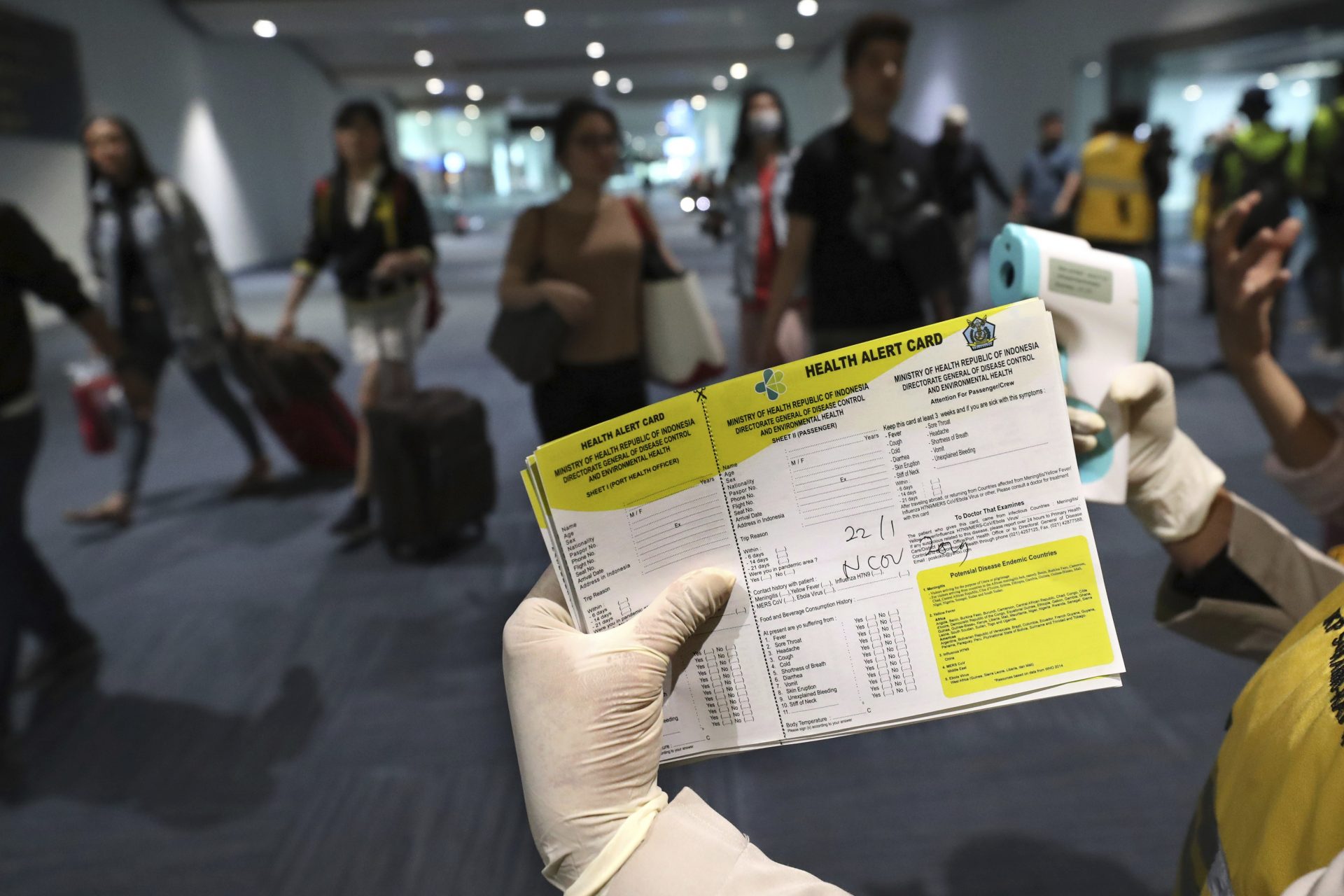 A health official holds a health alert card at the Soekarno-Hatta International Airport in Tangerang, Indonesia, Wednesday, Jan. 22, 2020. Indonesia is screening travelers from overseas for a new type of coronavirus as fears spread about a mysterious infectious disease after its first death reported in China.