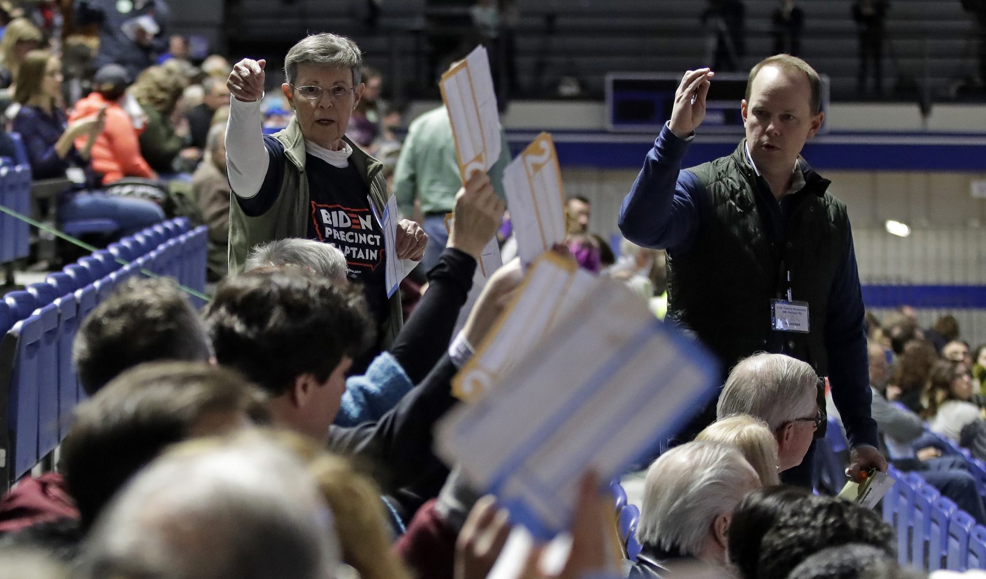 Caucus goers seated in the section for Democratic presidential candidate former Vice President Joe Biden hold up their first votes as they are counted at the Knapp Center on the Drake University campus in Des Moines, Iowa, Monday, Feb. 3, 2020.