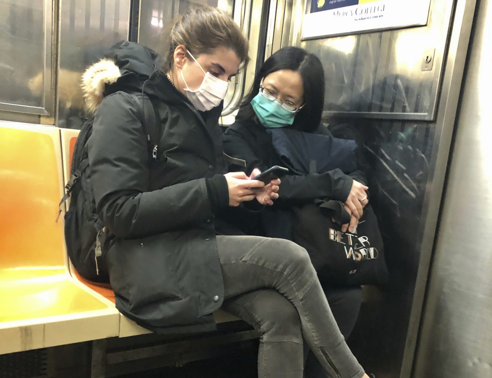 In this March 4, 2020 photo, two women wear masks as they ride a subway train, in New York. Two more cases of the new coronavirus have been confirmed in New York City, raising New York state's total to 13, Mayor Bill de Blasio said Thursday.