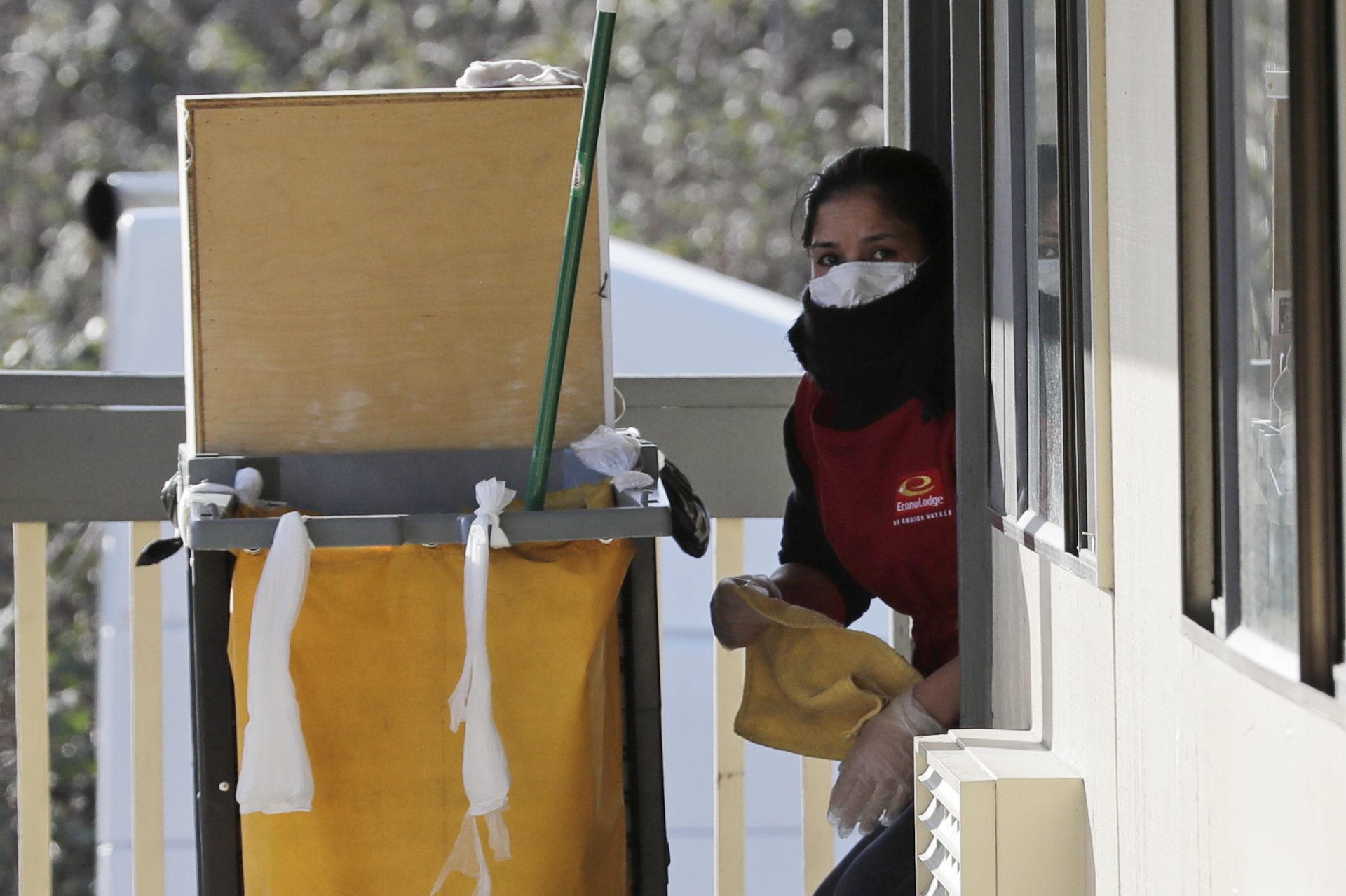 A housekeeping worker wears a mask as she cleans a room, Wednesday, March 4, 2020, at an Econo Lodge motel in Kent, Wash. King County Executive Dow Constantine said Wednesday that the county had purchased the 85-bed motel south of Seattle to house patients for recovery and isolation due to the COVID-19 coronavirus.