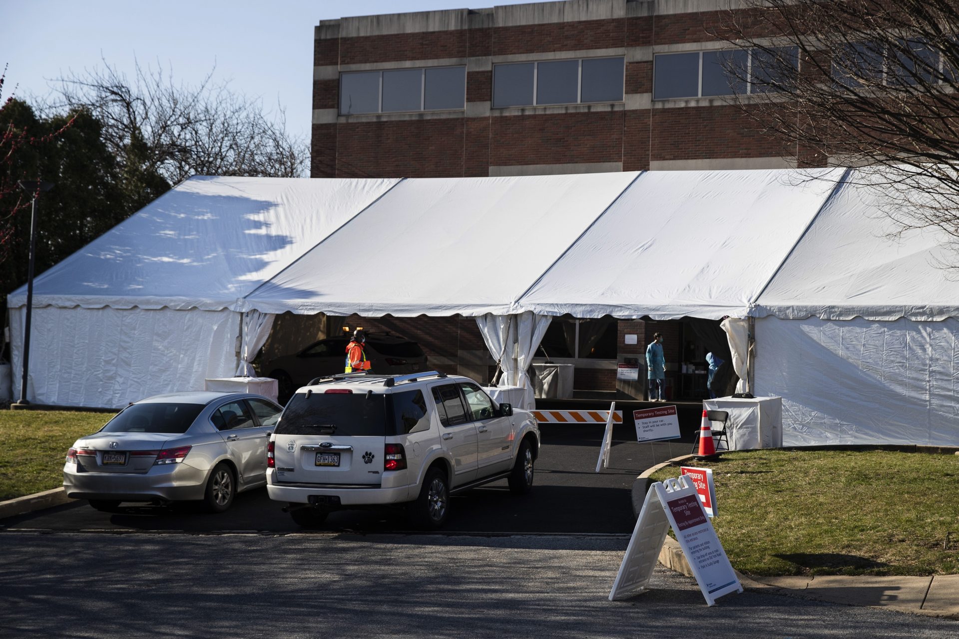 People in cars wait to enter a COVID-19 temporary testing site at Abington Hospital in Abington, Pa., Wednesday, March 18, 2020. For most people, the new coronavirus causes only mild or moderate symptoms. For some it can cause more severe illness.