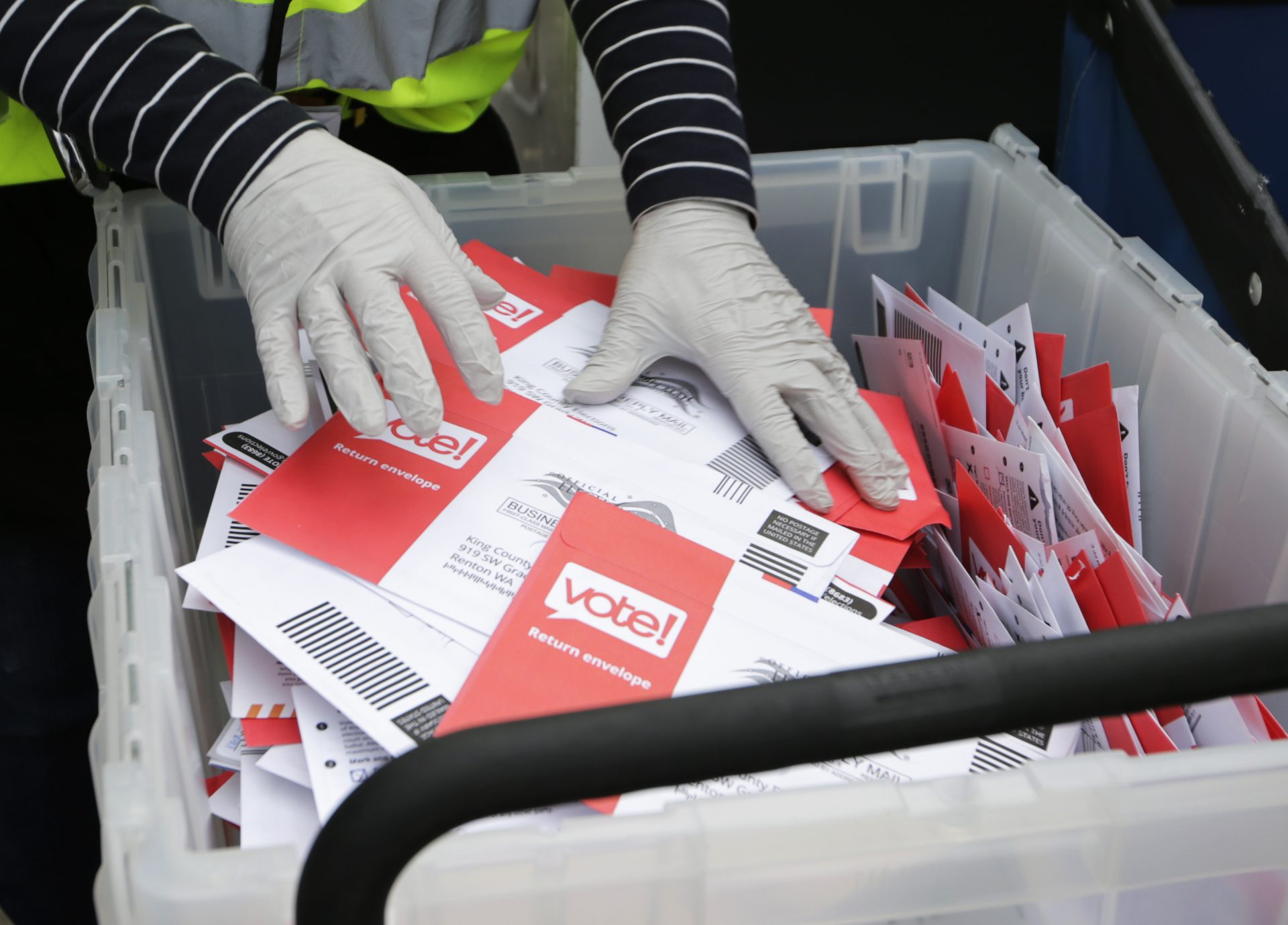 Wearing gloves, a King County Election worker collect ballots from a drop box in the Washington State primary, Tuesday, March 10, 2020, in Seattle. Washington is a vote by mail state.