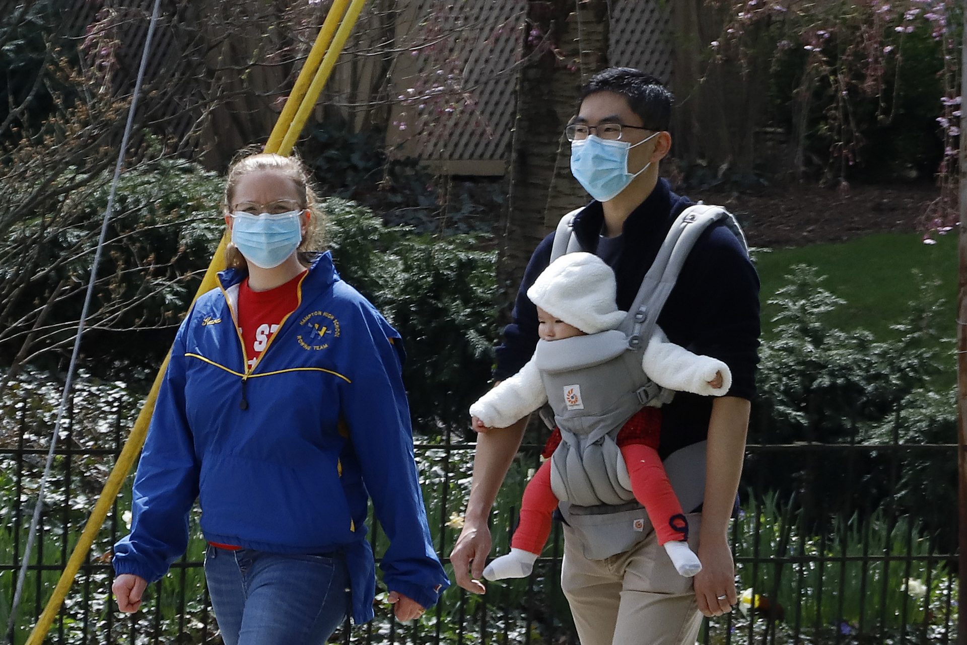 A couple out for walk wear protective masks on a warm afternoon in Pittsburgh, Sunday, April 5, 2020.