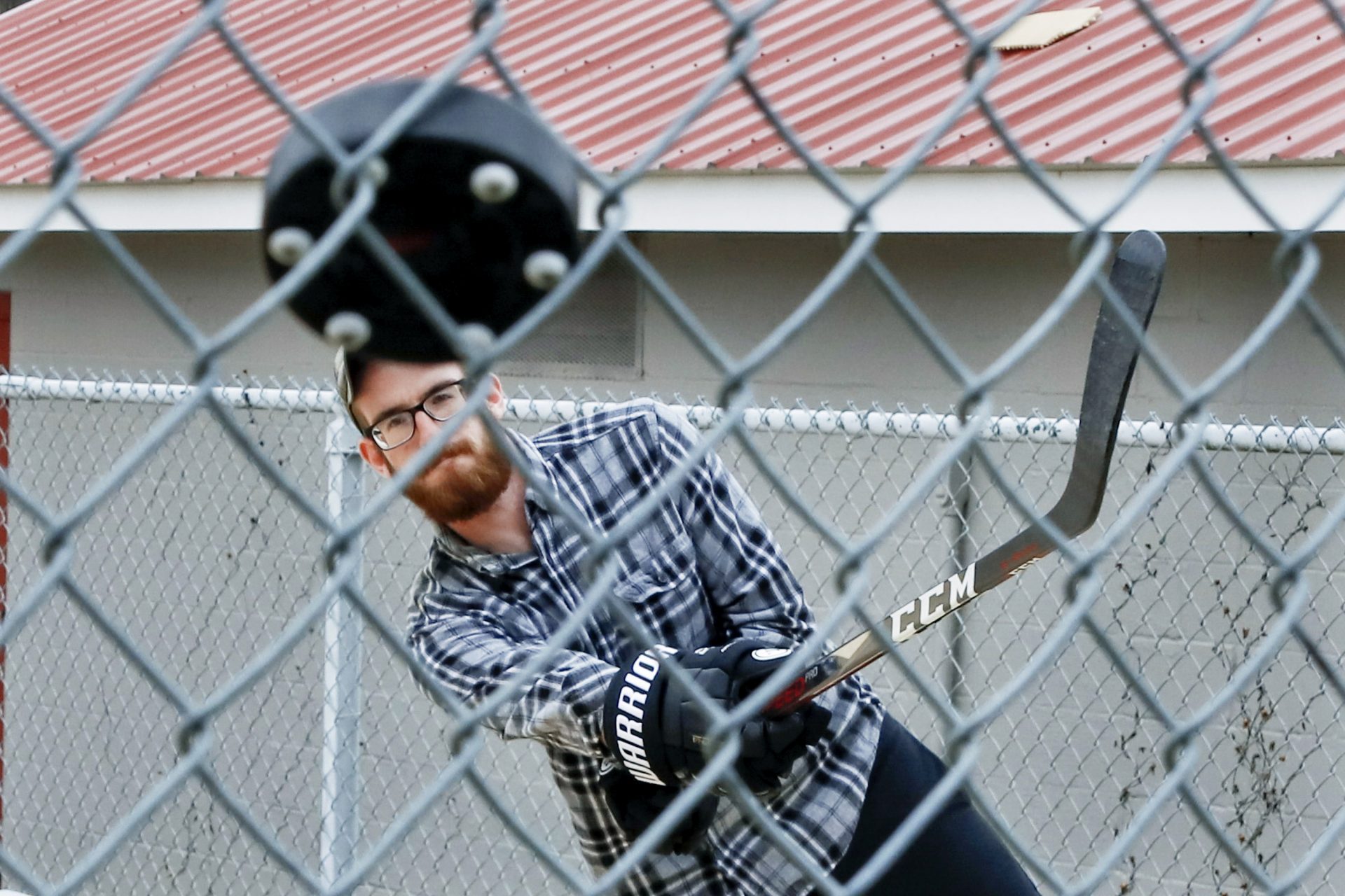 Jason Dapper, shoots a street hockey puck at the fence in one of the tennis courts at the local park as he practices his hockey skills with his wife, Friday, March 27, 2020, in Zelienople, Pa. The couple said they have taken to the park since the local rinks have closed with the outbreak of COVID-19.