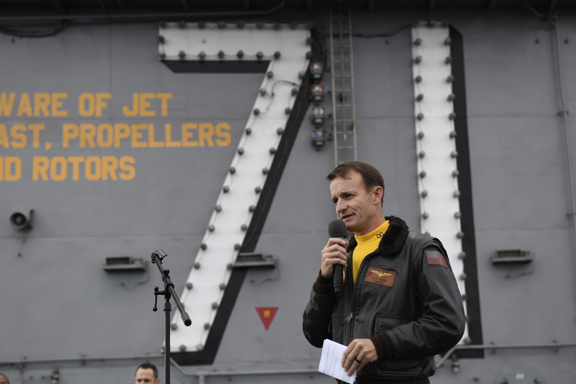 In this Nov. 15, 2019, photo U.S. Navy Capt. Brett Crozier, commanding officer of the aircraft carrier USS Theodore Roosevelt (CVN 71), addresses the crew during an all-hands call on the ship's flight deck while conducting routine operations in the Eastern Pacific Ocean. U.S. defense leaders are backing the Navy's decision to fire the ship captain who sought help for his coronavirus-stricken aircraft carrier, even as videos showed his sailors cheering him as he walked off the vessel. Videos went viral on social media Friday, April 3, 2020, showing hundreds of sailors gathered on the ship chanting and applauding Navy Capt. Brett Crozier as he walked down the ramp, turned, saluted, waved and got into a waiting car.