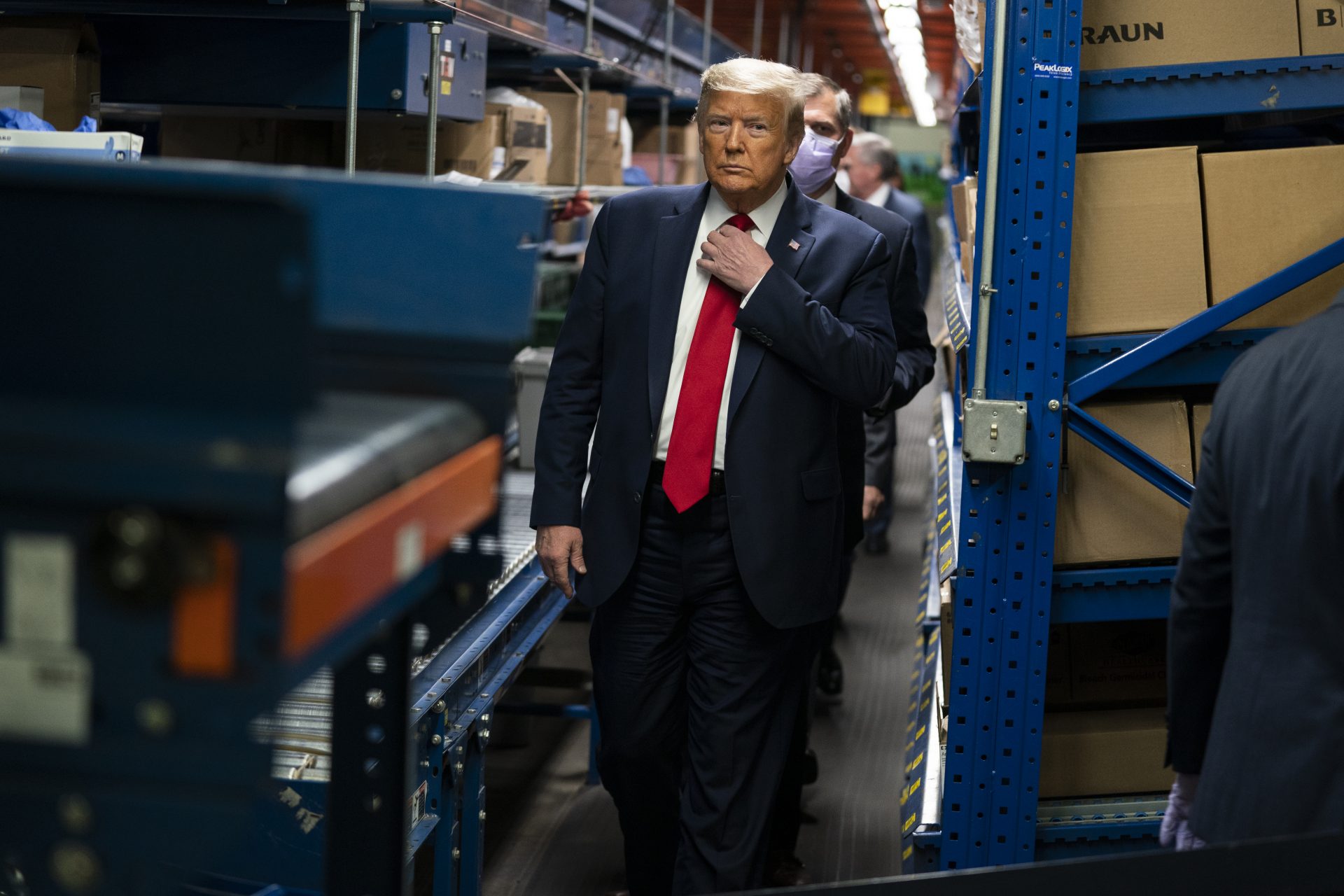 President Donald Trump adjusts his tie during a tour of Owens & Minor Inc., a medical supply company, Thursday, May 14, 2020, in Allentown,