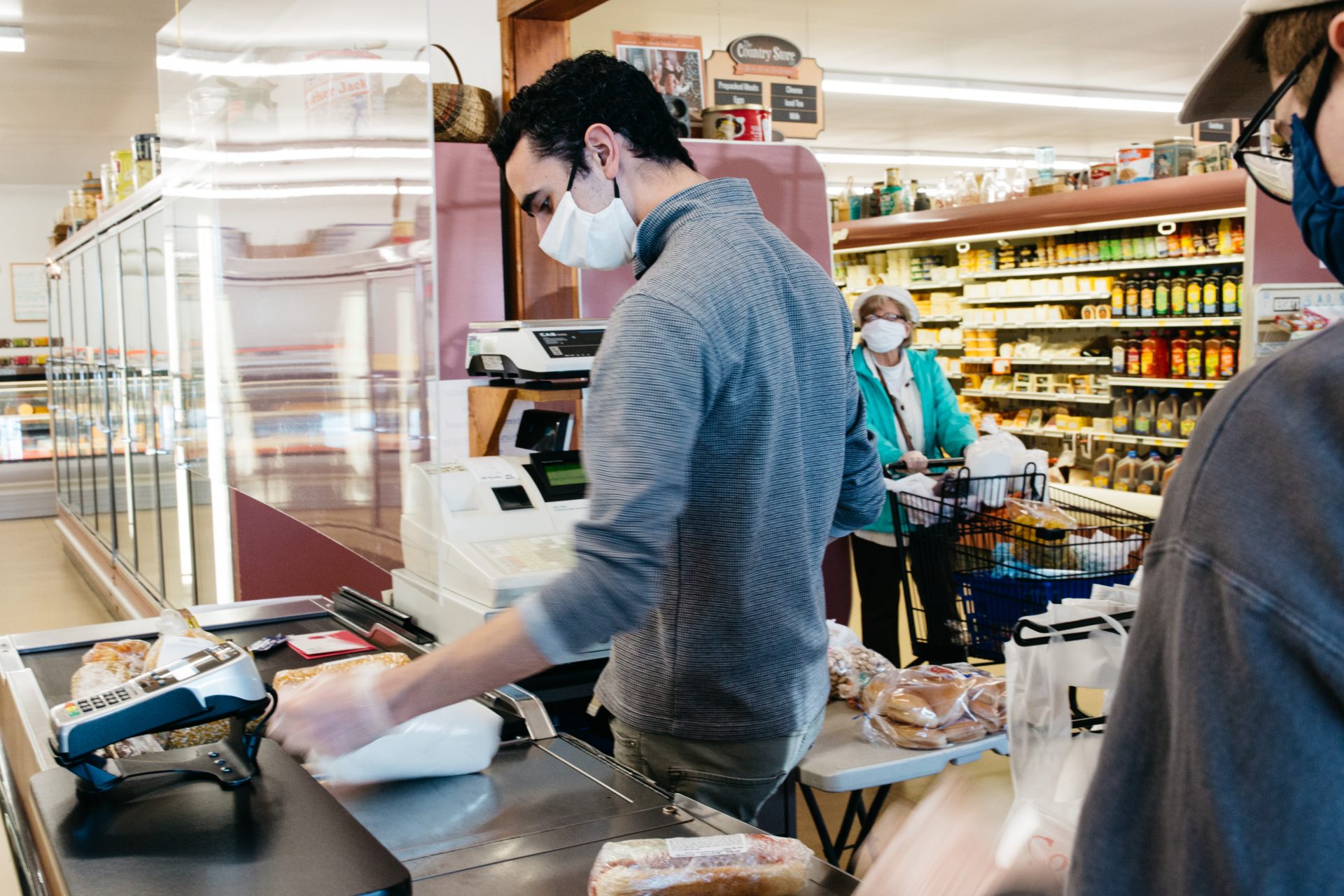 A cashier wears gloves and a face mask while assisting a customer at The Country Store on May 9, 2020, in Mount Joy, Pa.