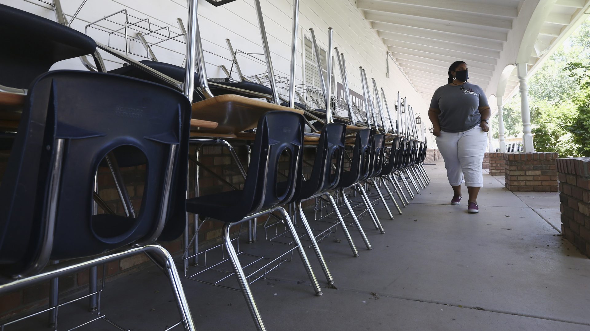 Kristina Washington, special education staff member at Desert Heights Preparatory Academy, walks past desks and chairs at the closed Glendale, Ariz., school in early June.