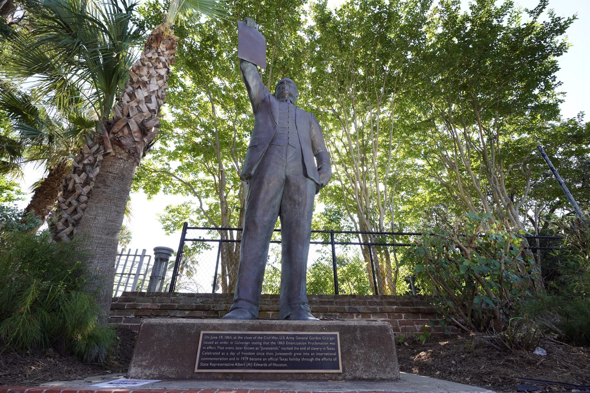 In this June 17, 2020, photo, a statue depicts a man holding the state law that made Juneteenth a state holiday in Galveston, Texas. The inscription on the statue reads "On June 19, 1865, at the close of the Civil War, U.S. Army General Gordon Granger issued an order in Galveston stating that the 1863 Emancipation Proclamation was in effect. That event, later known as "Juneteenth," marked the end of slavery in Texas. Celebrated as a day of freedom since then, Juneteenth grew into an international commemoration and in 1979 became an official Texas holiday through the efforts of State Representative Albert (AL) Edwards of Houston."
