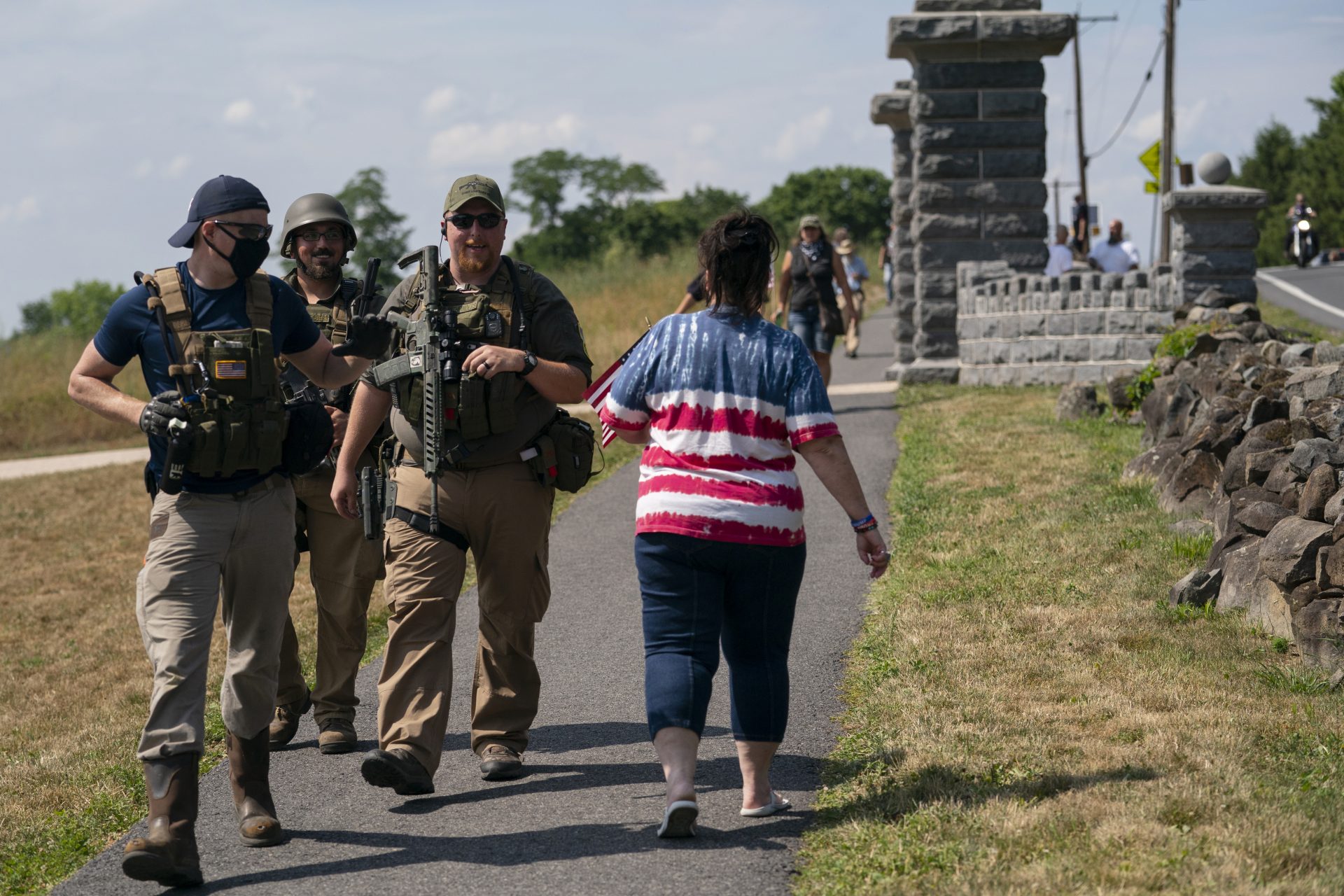 Members of a militia walk past a tourist as they patrol the area surrounding the Gettysburg National Cemetery Saturday, July 4, 2020, at Gettysburg National Military Park, in Gettysburg, Pa.