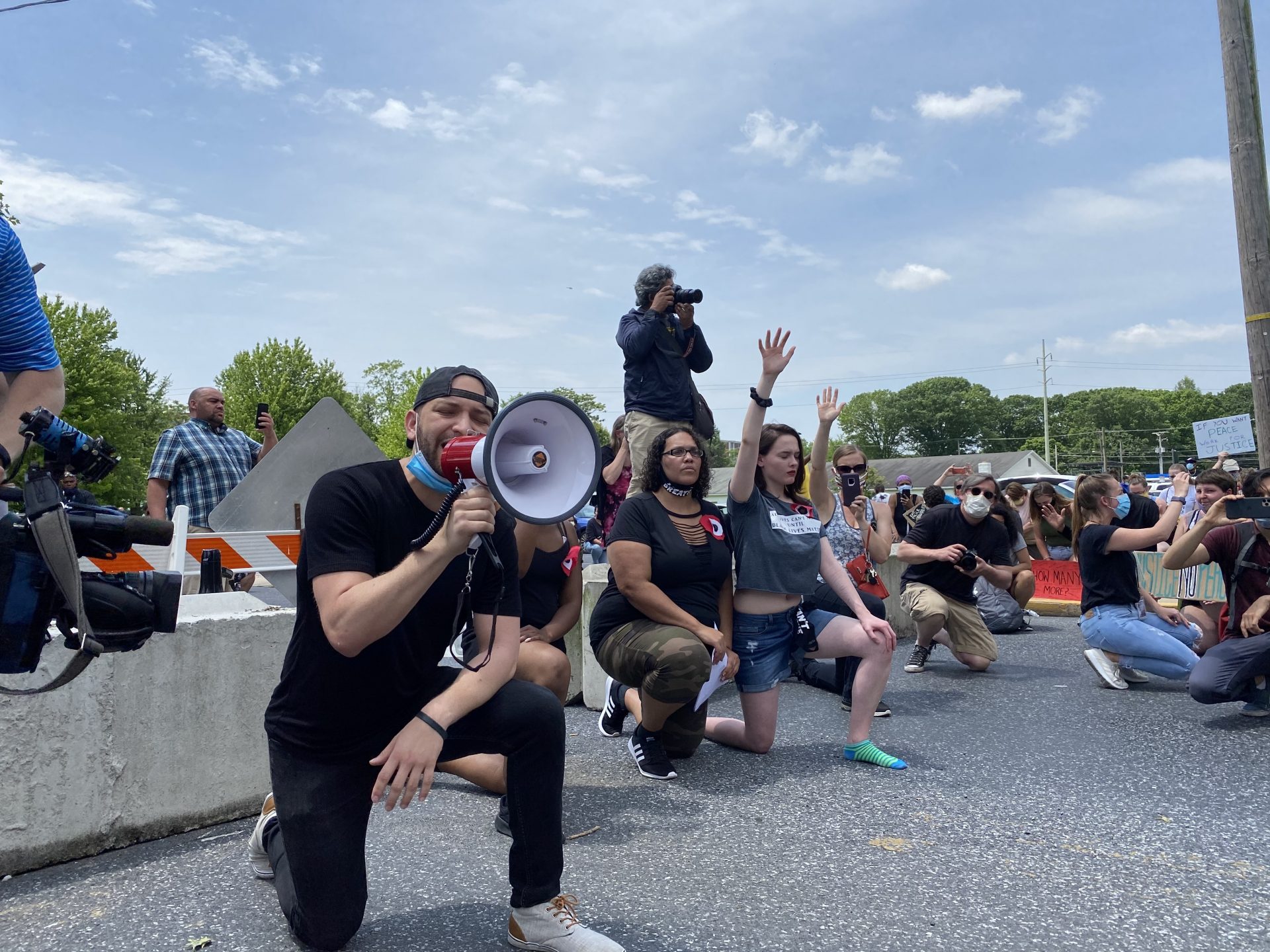 Michelle Cotton (middle), and Abigail Bragunier (right) kneel in front of protesters with Lebanon activist Amaury Abreu (left).