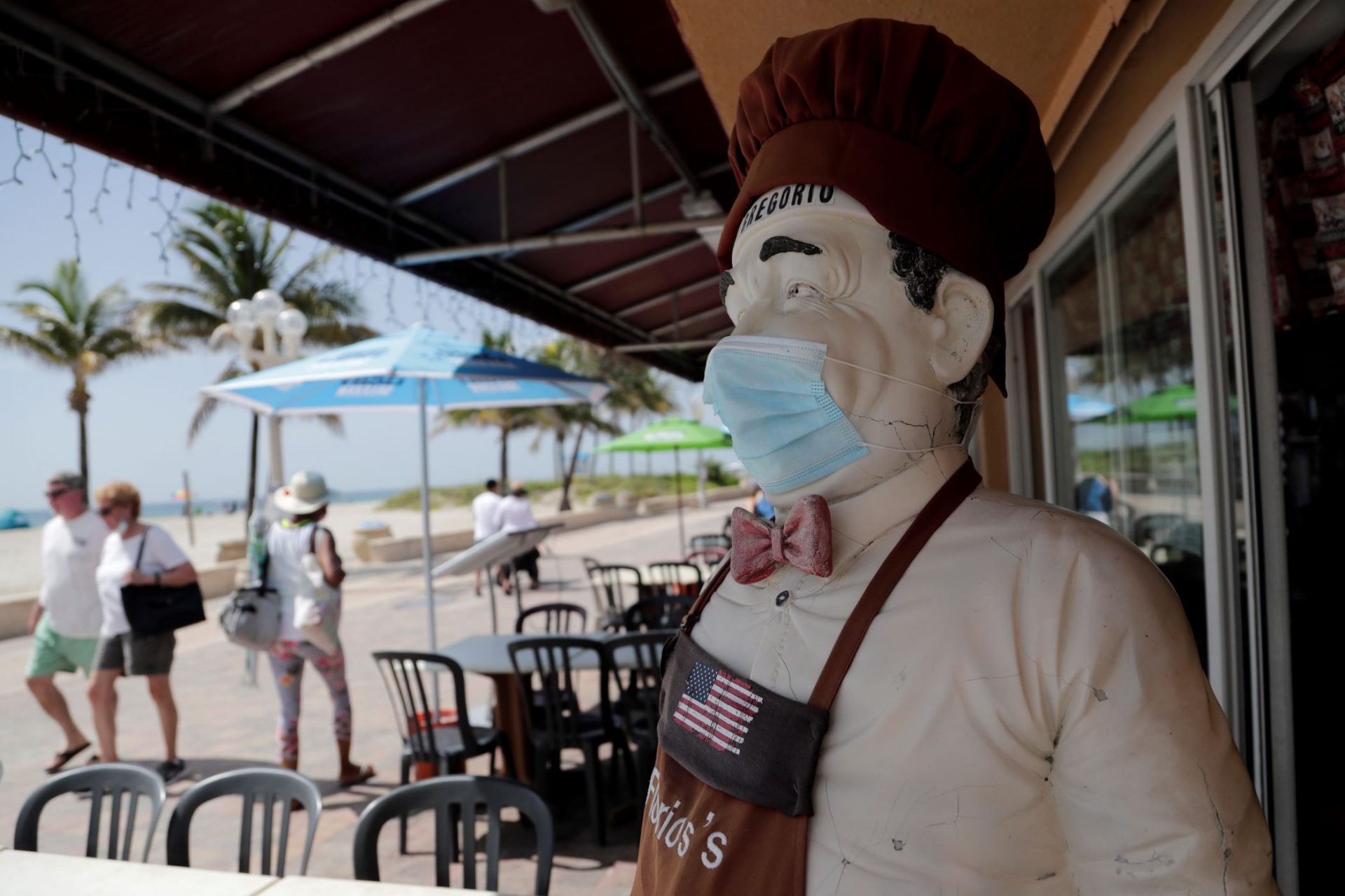 A statue of a chef at Florio's of Little Italy restaurant wears a protective face mask on the Hollywood Beach Broadwalk during the new coronavirus pandemic, Thursday, July 2, 2020, in Hollywood, Fla. In hard-hit South Florida, beaches from Palm Beach to Key West will be shut down for the Fourth of July holiday weekend. Restaurants and businesses along the Boardwalk will remain open.