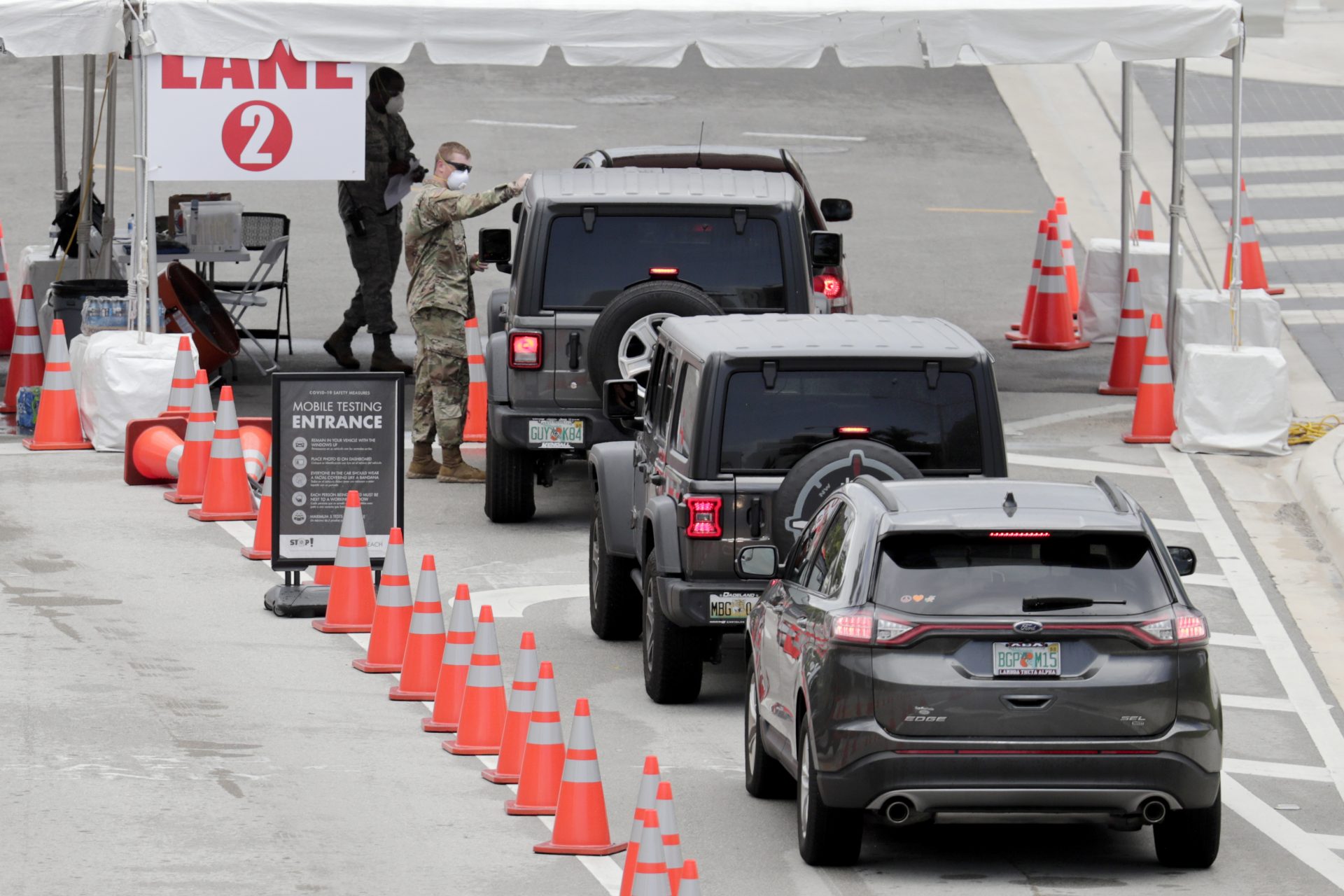 A member of the Florida National Guard directs vehicles at a COVID-19 testing site at the Miami Beach Convention Center during the coronavirus pandemic, Sunday, July 12, 2020, in Miami Beach, Fla. Florida on Sunday reported the largest single-day increase in positive coronavirus cases in any one state since the beginning of the pandemic.