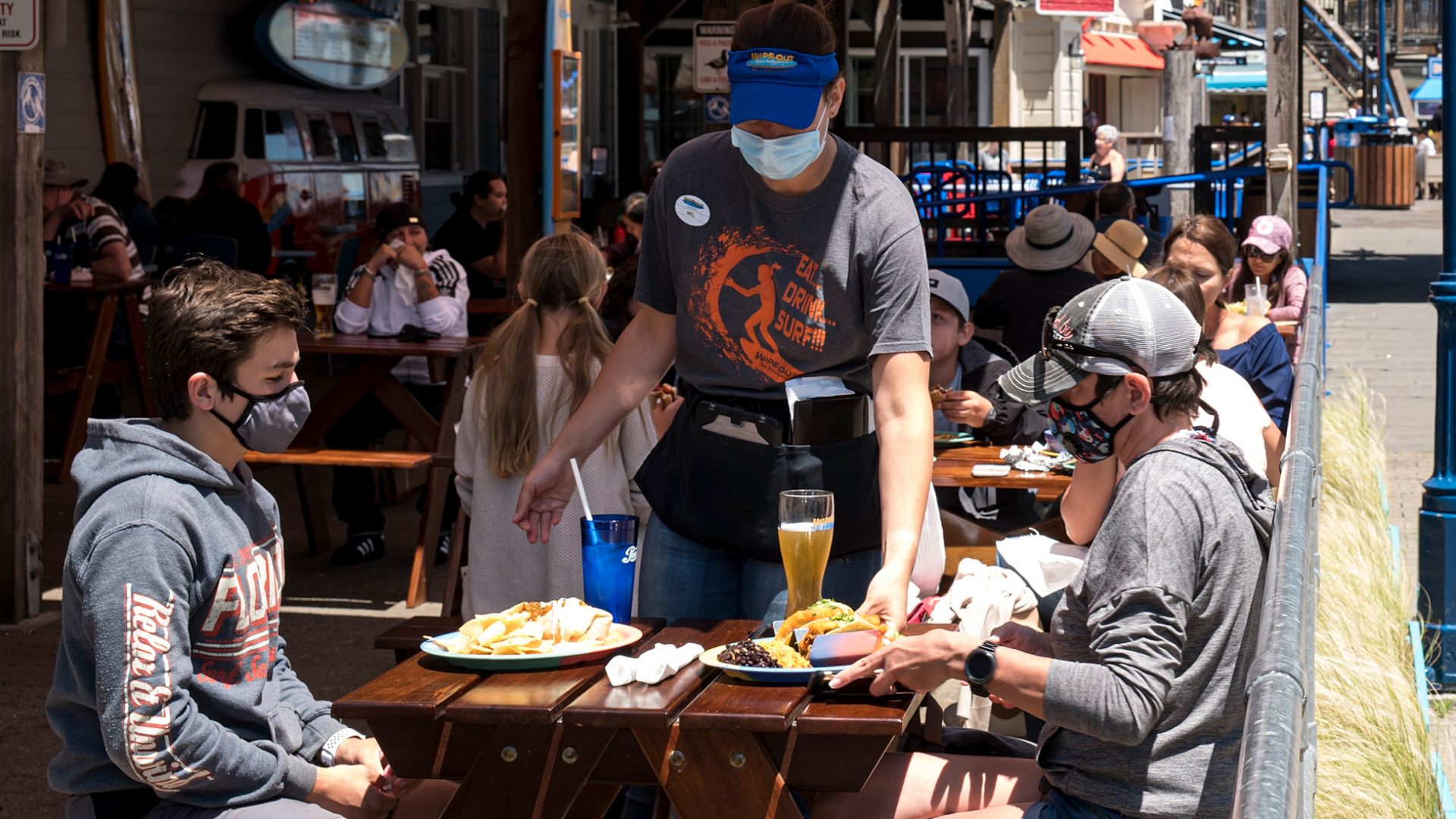 More than 20 U.S. states now require face masks, as officials hope to curb a sharp rise in new coronavirus cases. Here, patrons wear masks as they sit in the outdoor patio of a restaurant on Pier 39 at Fisherman's Wharf in San Francisco.