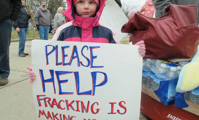 In this photo from 2012, Skylar McEvoy holds up a sign at a rally in Butler, Pa. She and her family moved after they say fracking polluted their water. 