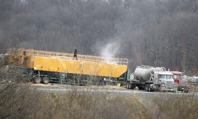 In this photo made on Saturday, Feb. 16, 2013, a worker walks on top of a container of chemicals used in the making of a brine water that is then pumped below the surface in a hydraulic fracturing process to release natural gas from shale deposits at a gas well site in Zelienople, Pa. 