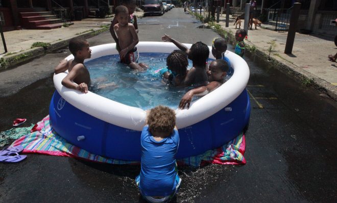 In this June 2012 photo, Michael Hall, 2, pulls down the edge of the pool while others swim  in Philadelphia. Climate change has already brought hotter weather to the state, where some areas have warmed 2 degrees in 30 years.