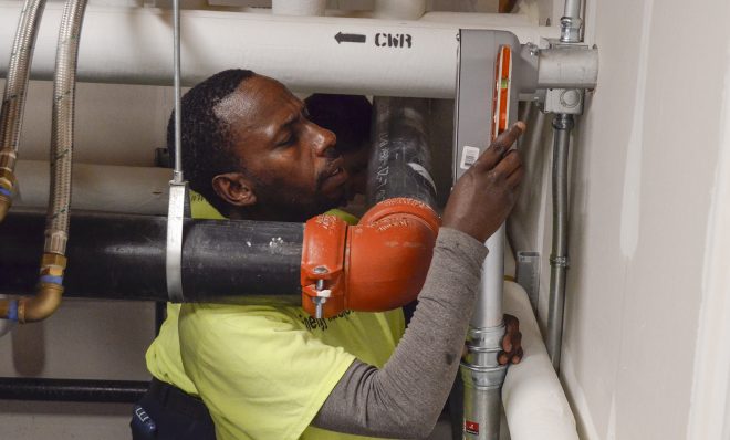 Richard Tumushime, an electrician with Pittsburgh-based Energy Independent Solutions, works with a crew to put the finishing touches on wiring a solar panel system at the new Forest Hills Municipal Building.