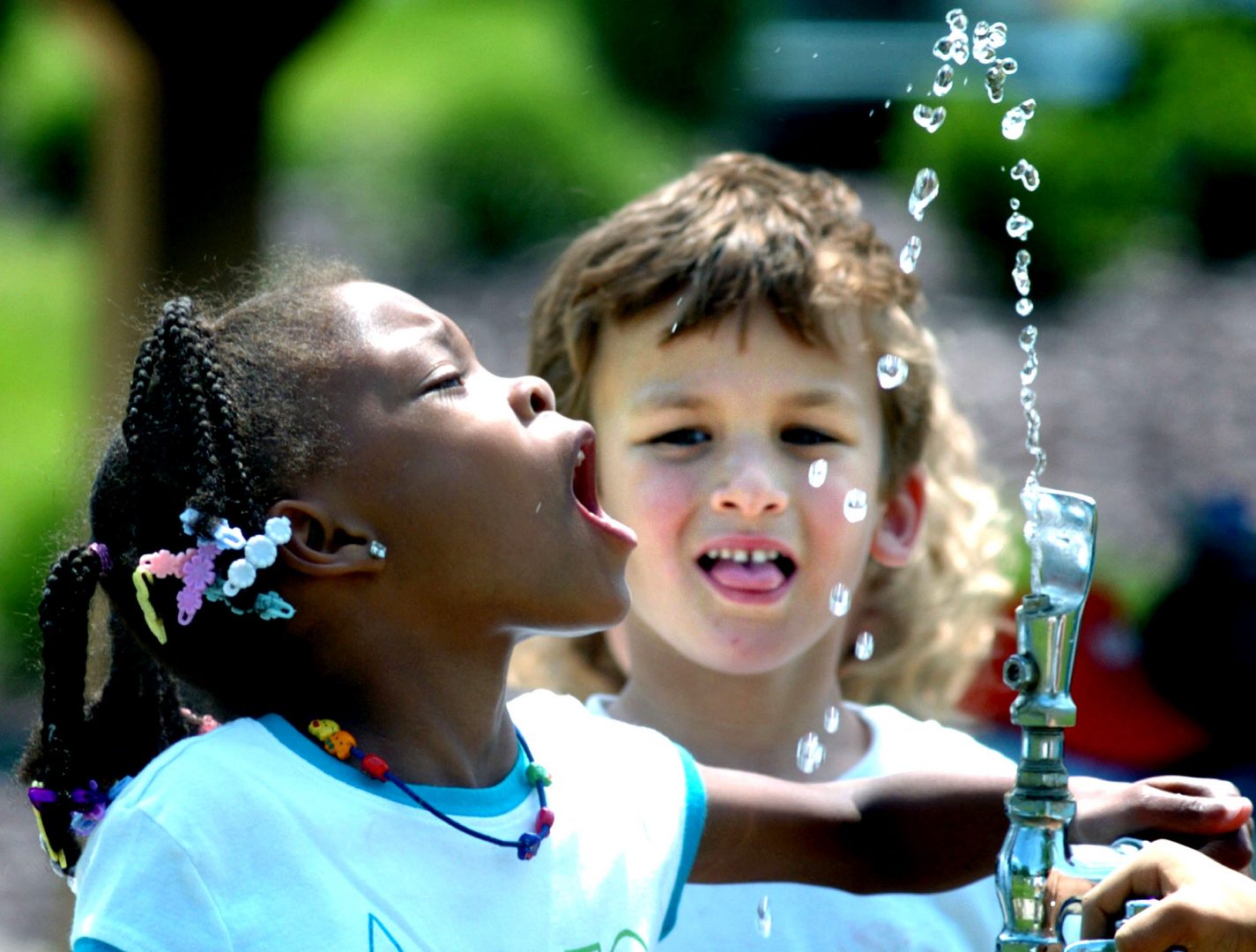 FILE - In this June 3, 2008 file photo, Liberty Valley Elementary School, then, kindergarten student Tianna Swisher moves into an arc of water for a drink at the water fountain at Montour Preserve, near Washingtonville, Pa. , while classmate Eli Zakarian awaits his turn. Consumers know less about the water they pay dearly for in bottles than the tap water they can drink almost for free because they're regulated differently, the Government Accountability Office and a group of scientists say in reports being released Wednesday, July 8, 2009.