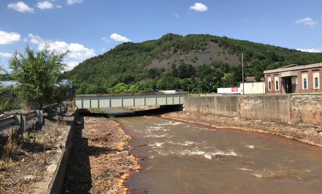 FILE PHOTO: (Shamokin, Northumberland County) Shamokin Creek is colored orange from acid mine drainage. In the background, a mountain of waste coal towers over the town.