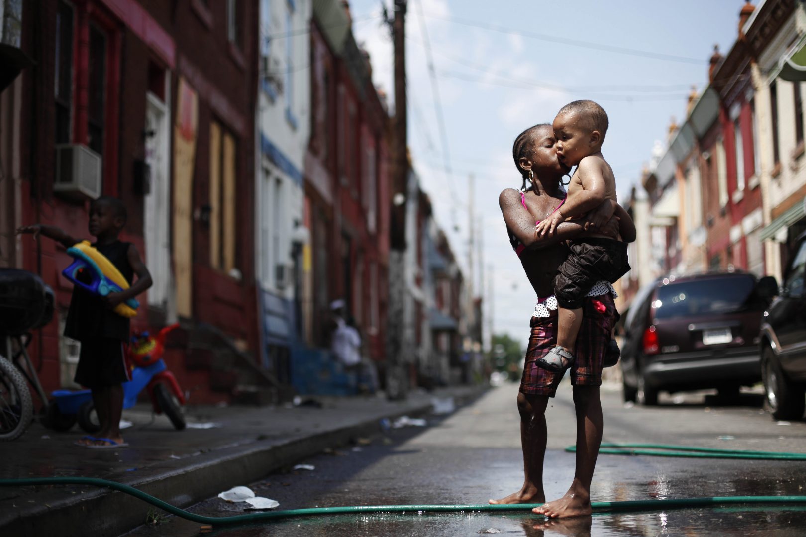 In this photo from July 2011, Aniyah Davis kisses her cousin William Respes as they play in water from a garden hose during a  heat wave in Philadelphia.  