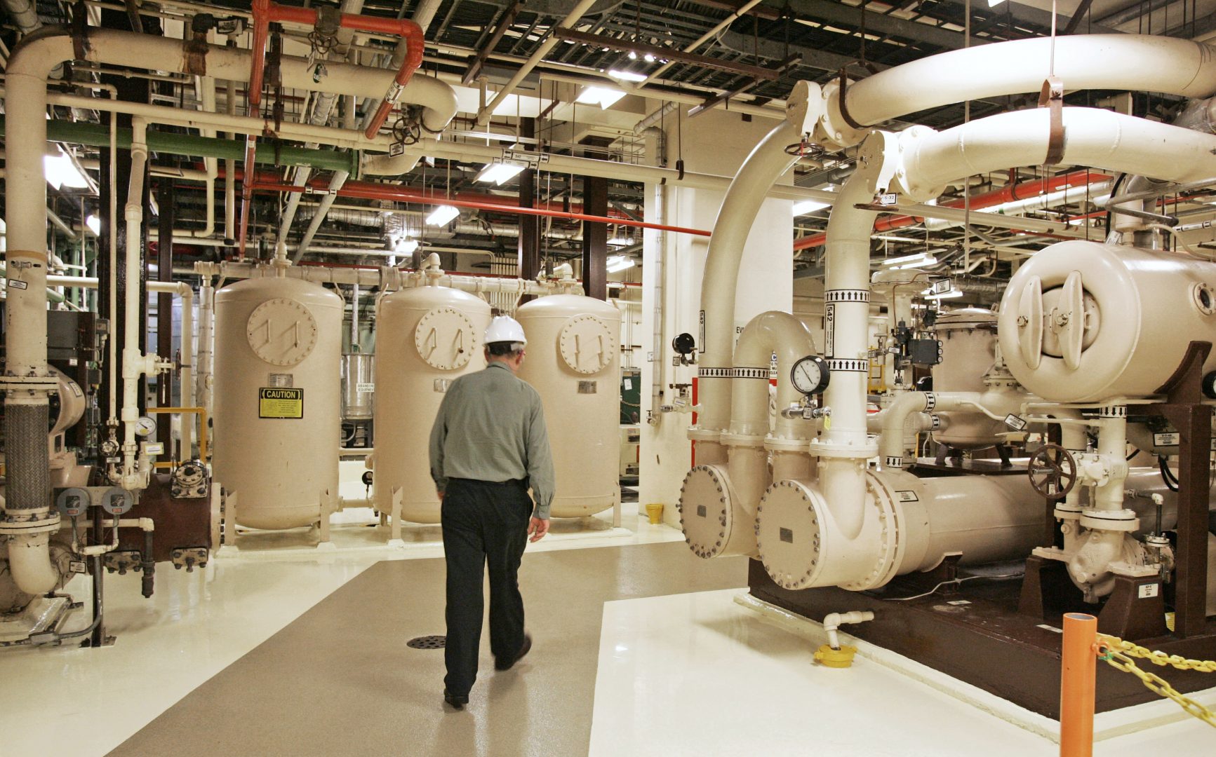 In this Feb. 25, 2010, file photo, an Exelon Corp. employee walks past equipment in the turbine building at the Oyster Creek Generating Station, a nuclear power plant in Lacey Township, N.J. Shutting down the site of the nation's oldest nuclear power plant will take 60 years and cost $1.4 billion, according to a plan filed May 21, 2018, by a subsidiary of Chicago-based Exelon Corp. and under review by the Nuclear Regulatory Commission. 