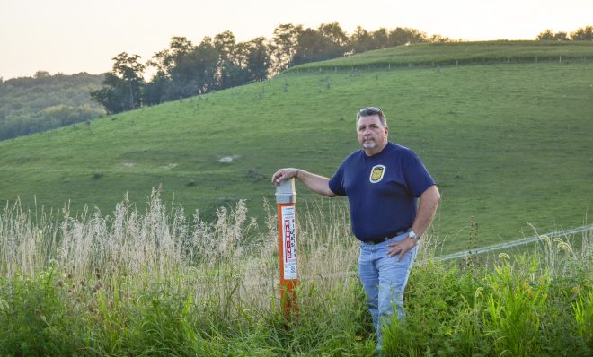 Chief Bob Rosatti of the Forbes Road Volunteer Fire Department stands alongside a marker for the Texas Eastern Transmission Pipeline, which exploded here in Salem Township in 2016.