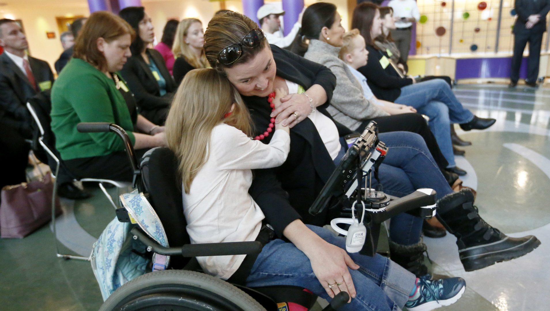 FILE PHOTO: Eight-year-old Abigail Gabriel, center, hugs her mother, Erin, from her wheelchair as Pennsylvania Department of Human Services Acting Secretary Teresa Miller, Thursday, Dec. talks about the Children's Health Insurance Program, CHIP, during a news conference, Dec. 7, 2017, in Pittsburgh.  