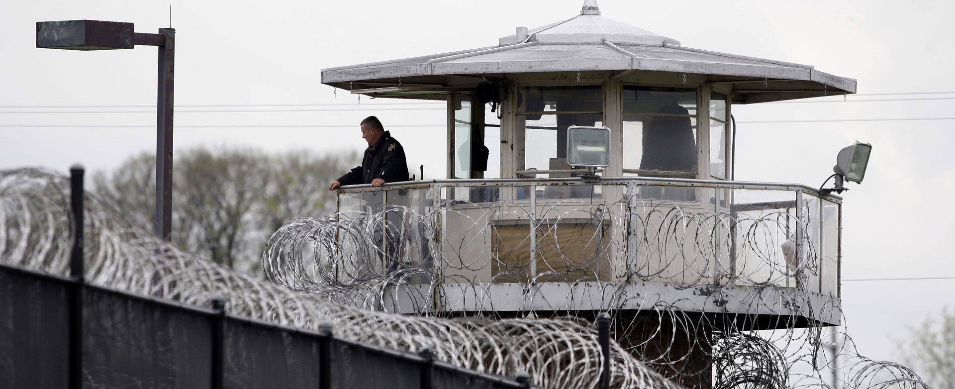 A solitary corrections officer looks out from a tower at one corner of the state prison in Camp Hill.