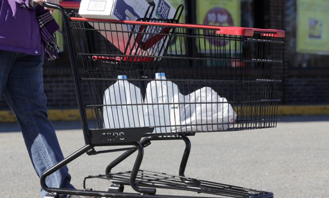 In this Friday, Feb. 26, 2016 photo, a woman leaves a Tops supermarket with bottled water that is being supplied to residents in Hoosick Falls, N.Y. PFOA, long used in the manufacuring of Teflon pans, Gore-Tex jackets, ski wax, and many other products has turned up in the water in factory towns around the country like Hoosick Falls, impacting drinking water.