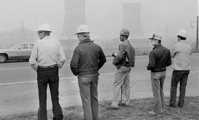 Workers from Metropolitan Edison's Three Mile Island nuclear plant stand outside visitors center early on March 30, 1979, as two cooling towers from the nuclear plant are visible in the background. Officials at the site declared an "on-site emergency" later Friday morning. (Rusty Kennedy/AP)