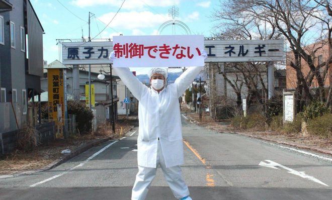 As a boy, Yuji Onuma won a contest to create the town slogan for Futaba, Japan. His phrase -- "Atomic power: energy for a bright future" -- was enshrined on an archway over the town's main street. But after the Fukushima nuclear accident in 2011, Onuma -- like many in Japan -- has turned against what he used to champion. Here, he stands in front of the archway holding a banner that modifies his slogan as statements opposing nuclear energy.
