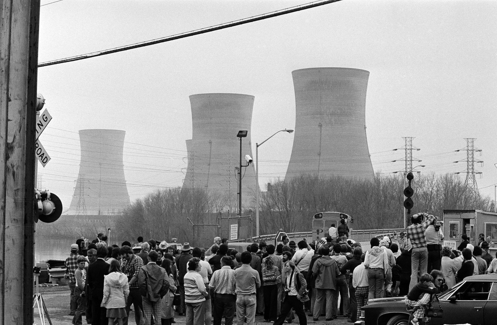 FILE PHOTO: Newsmen and spectators stand in front of the main gate of the Three Mile Island Nuclear Generating Station in Middletown, Penn., April 2, 1979.