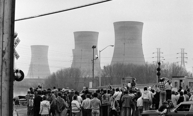 FILE PHOTO: Newsmen and spectators stand in front of the main gate of the Three Mile Island Nuclear Generating Station in Middletown, Penn., April 2, 1979.