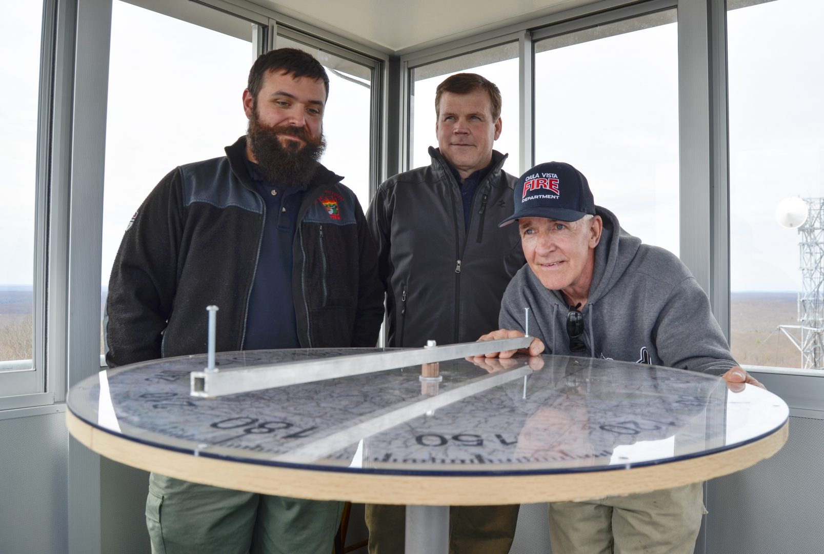 Officials from the Moshannon Forest District gather around the alidade, an instrument used to help personnel staffing lookout towers pinpoint the location of wildfires. From left to right, Joe Polaski, John Hecker and Larry Bickel stand in the new Chestnut Ridge tower.