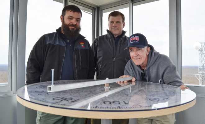 Officials from the Moshannon Forest District gather around the alidade, an instrument used to help personnel staffing lookout towers pinpoint the location of wildfires. From left to right, Joe Polaski, John Hecker and Larry Bickel stand in the new Chestnut Ridge tower.