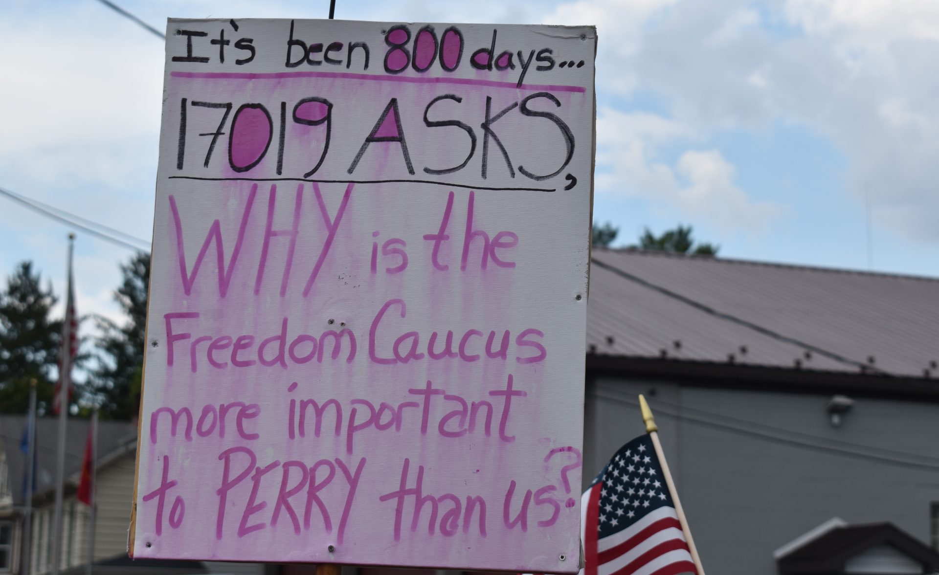 A protester holds a sign criticizing U.S. Rep. Scott Perry, R-Pa., outside the Hummelstown Fire Department on July 30, 2019.