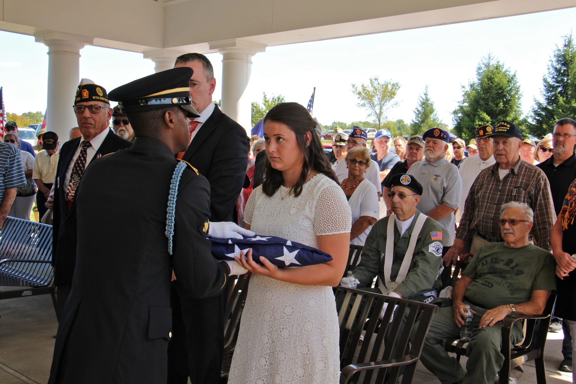 Justine Newman, an intern at the Bucks County Coroner's Office who helped to identify veterans among the office's unclaimed remains, is presented with a memorial flag during the service for 14 veterans who died unattended.
