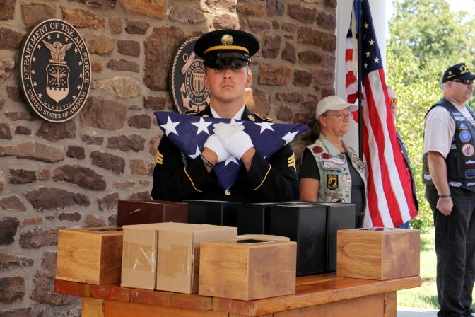 An Army National Guard soldier stands behind the cremated remains of 14 veterans who died whose remains were unclaimed.