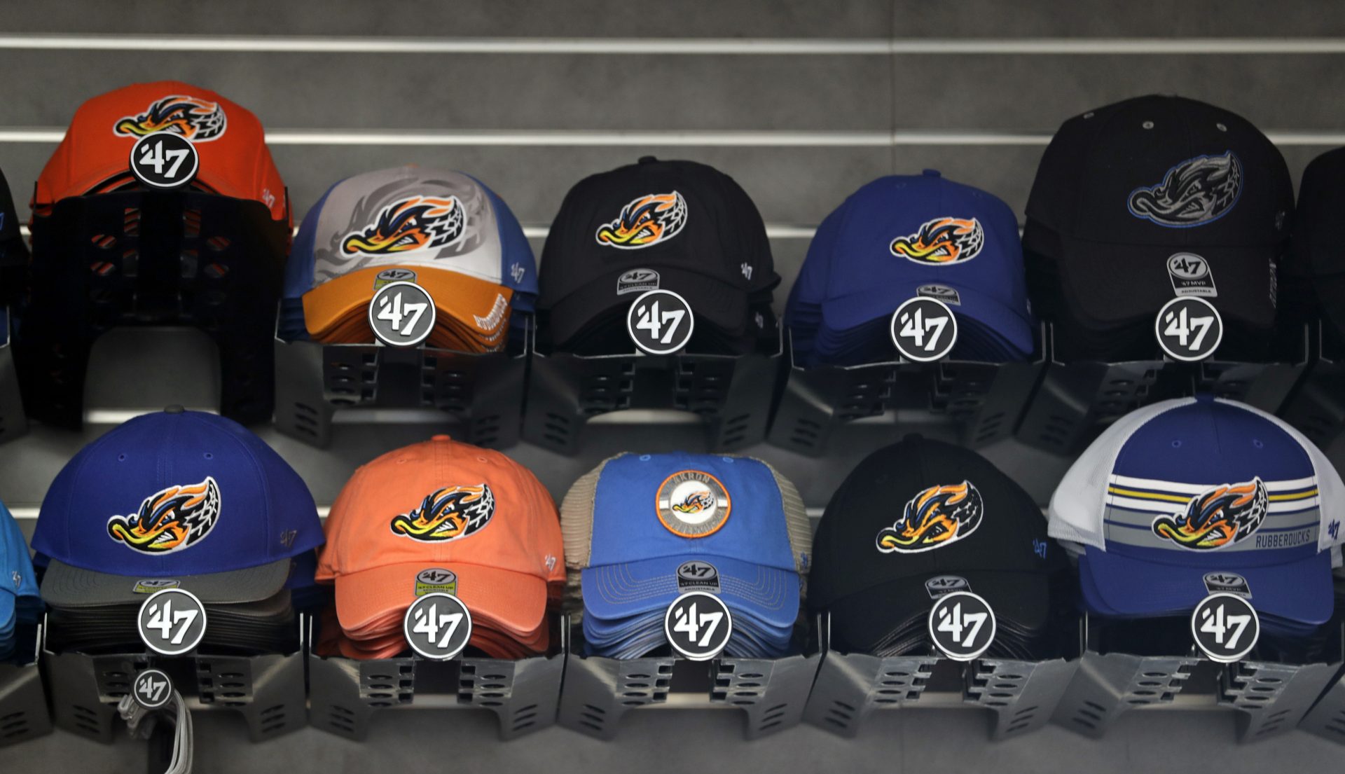 Caps carrying Akron Rubber Ducks branding rest on a shelf at the team shop before a minor-league baseball game between Akron and Bowie, Thursday, April 18, 2019, in Akron, Ohio.