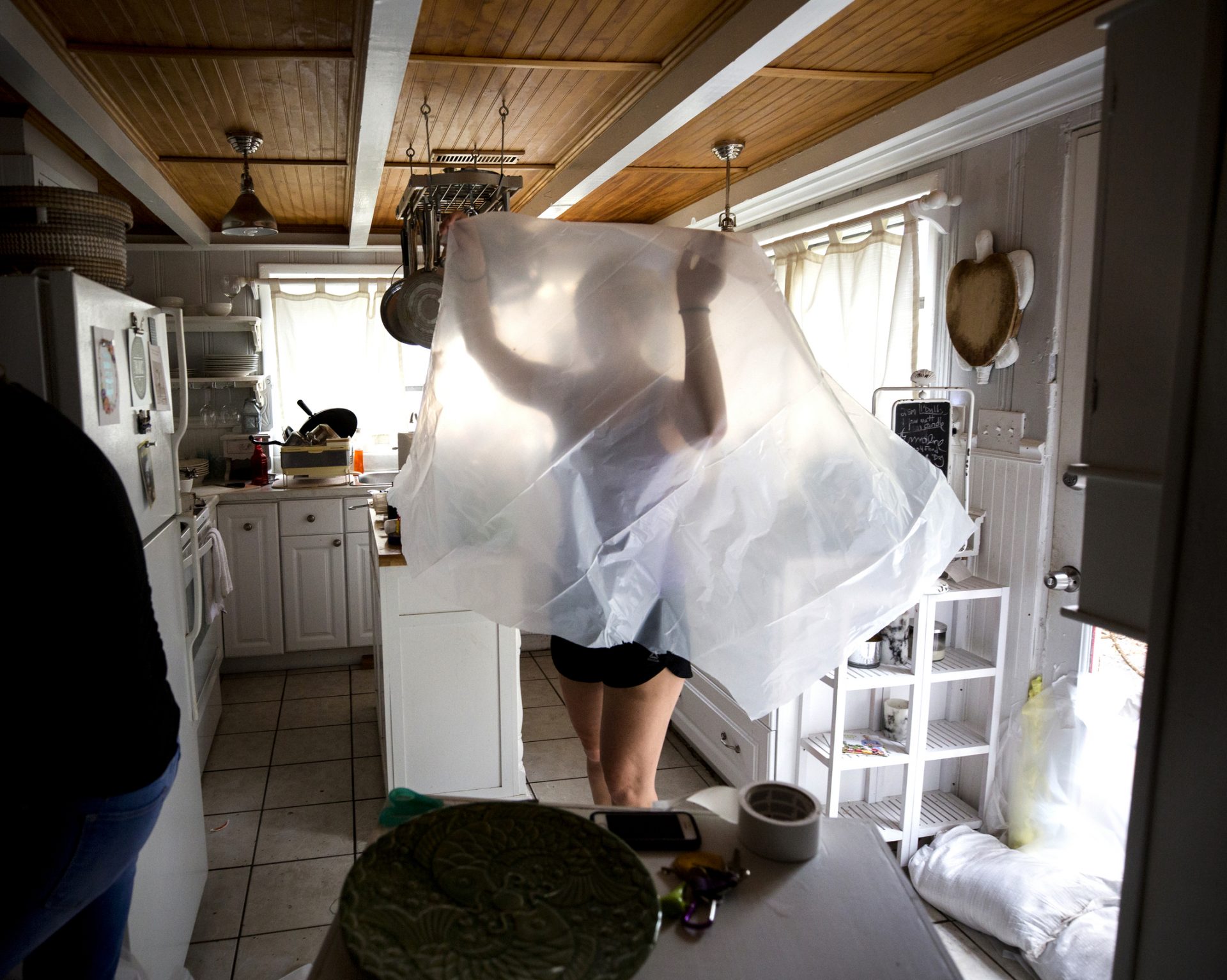 Allie Hayser holds a sheet of plastic as her roommate Fran Galloway prepares to tape it over her washing machine before Hurricane Dorian brings storm surge and tropical storm winds, Wednesday, Sept. 4, 2019, in Tybee Island, Ga. 