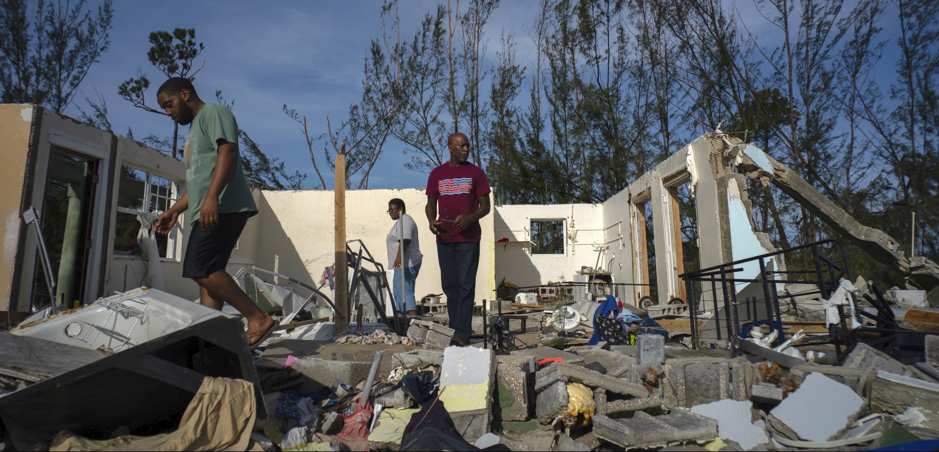 George Bolter, left, and his parents walk through the remains of his home destroyed by Hurricane Dorian in the Pine Bay neighborhood of Freeport, Bahamas, Wednesday, Sept. 4, 2019. Rescuers trying to reach drenched and stunned victims in the Bahamas fanned out across a blasted landscape of smashed and flooded homes Wednesday, while disaster relief organizations rushed to bring in food and medicine.