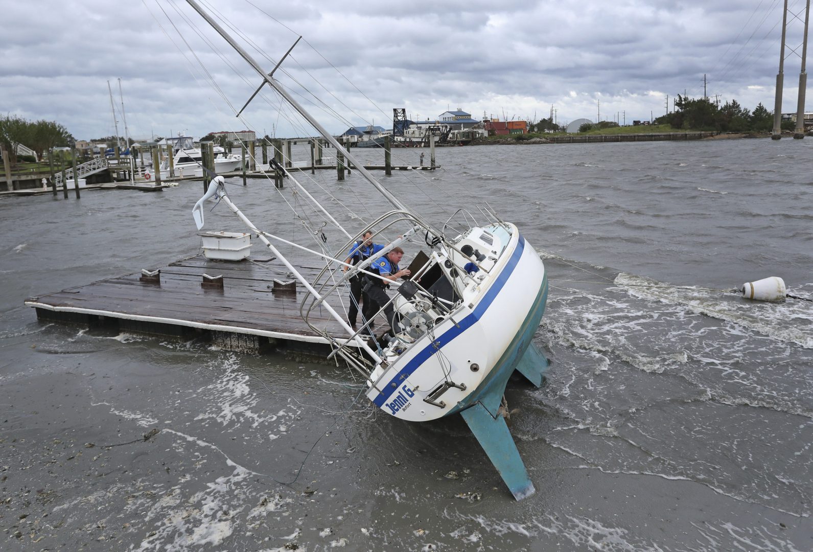 Beaufort Police Officer Curtis Resor, left, and Sgt. Micheal Stepehens check a sailboat for occupants in Beaufort, N.C. after Hurricane Dorian passed the North Carolina coast on Friday, Sept. 6, 2019. Dorian howled over North Carolina's Outer Banks on Friday — a much weaker but still dangerous version of the storm that wreaked havoc in the Bahamas — flooding homes in the low-lying ribbon of islands and throwing a scare into year-round residents who tried to tough it out.