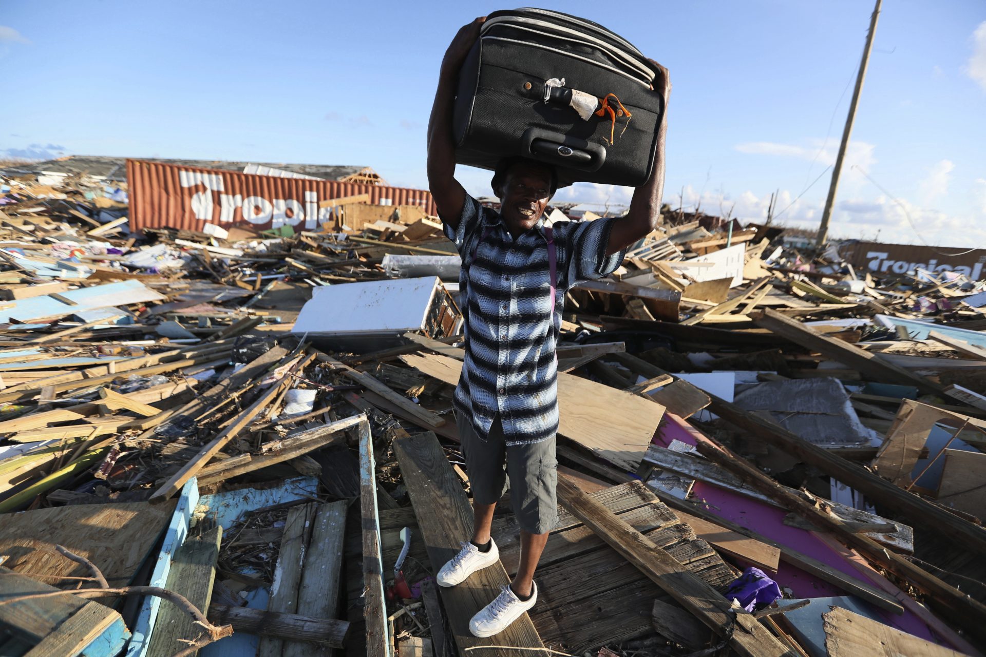 A man carries clothes over what remains of homes in the area called The Mudd after it was devastated by Hurricane Dorian, as he prepares to evacuate Abaco Island, Bahamas, Sunday, Sept. 8, 2019. Dorian was the most powerful hurricane in the northwestern Bahamas' recorded history.